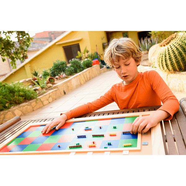 Boy sorting colored magnets on a checkered board in a Montessori Homeschool