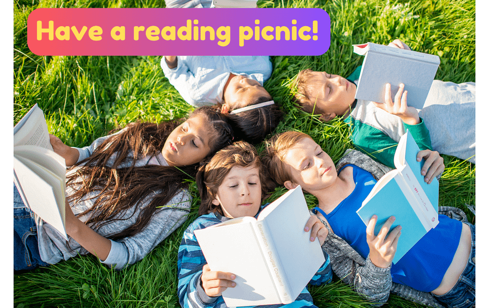 Kids reading and having a summer reading picnic while reading books in the grass.